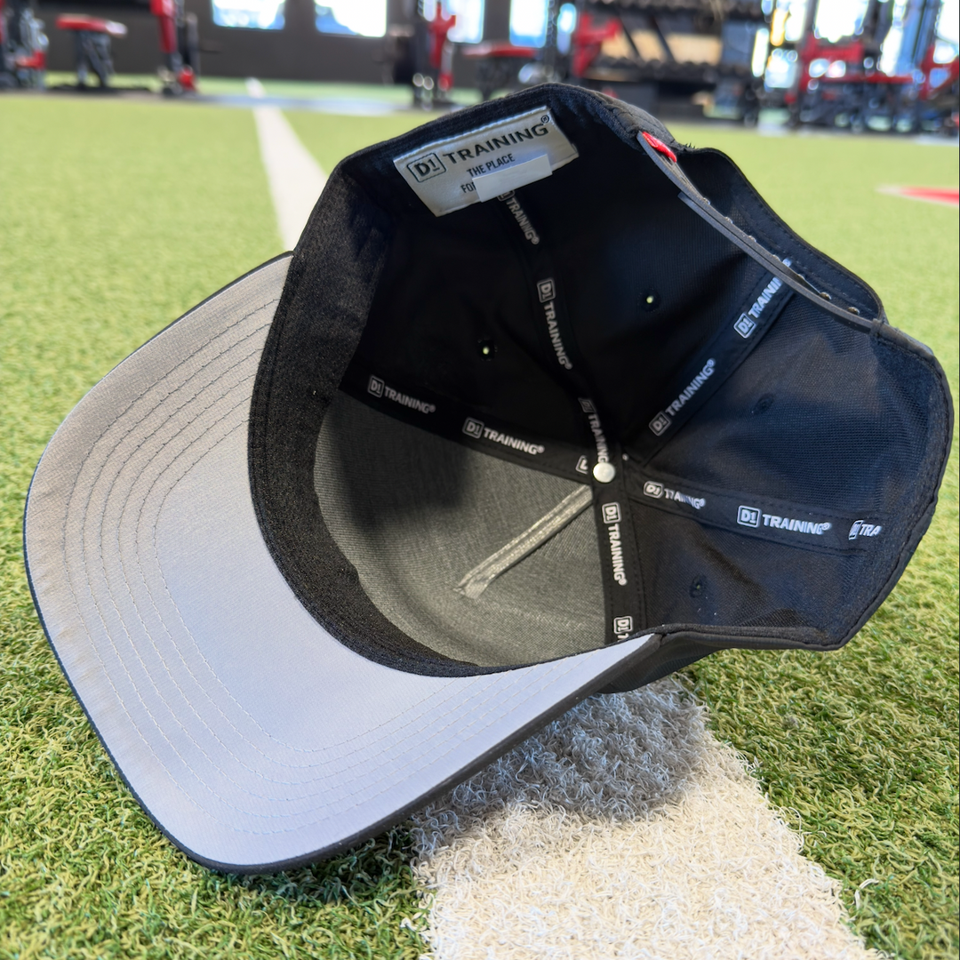 Black and gray cap on a golf course with visible branding